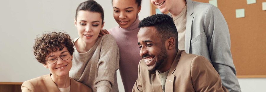 Group of people using a laptop and discussing something and laughing together.