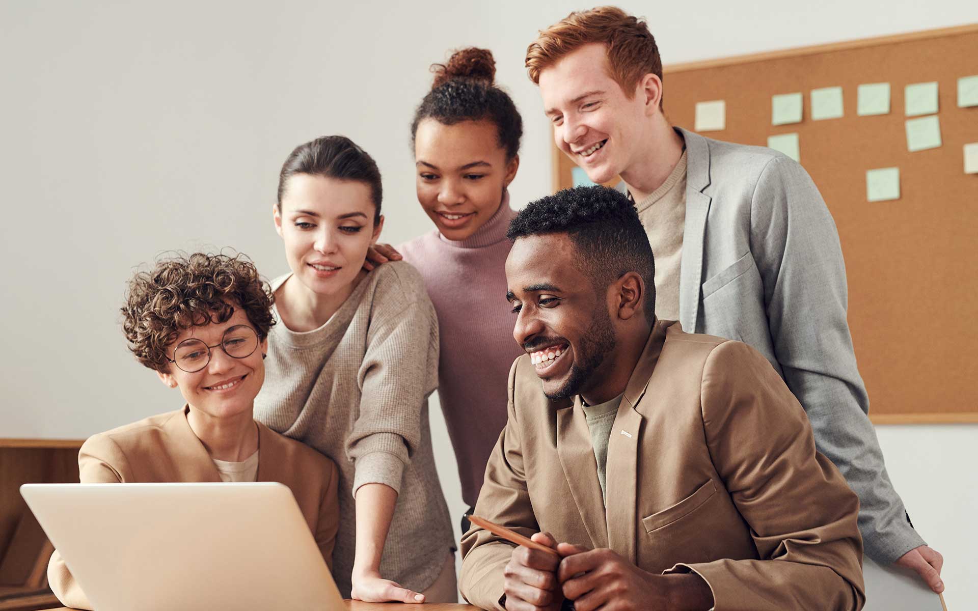 Group of people using a laptop and discussing something and laughing together.