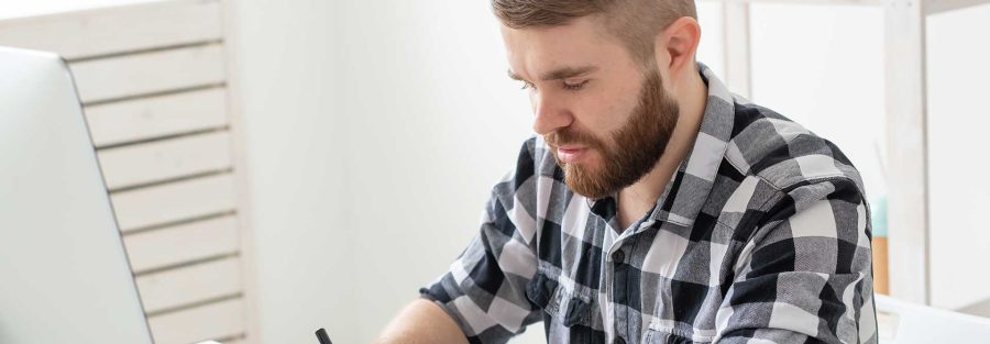 Man using a tablet while sitting in front of a laptop