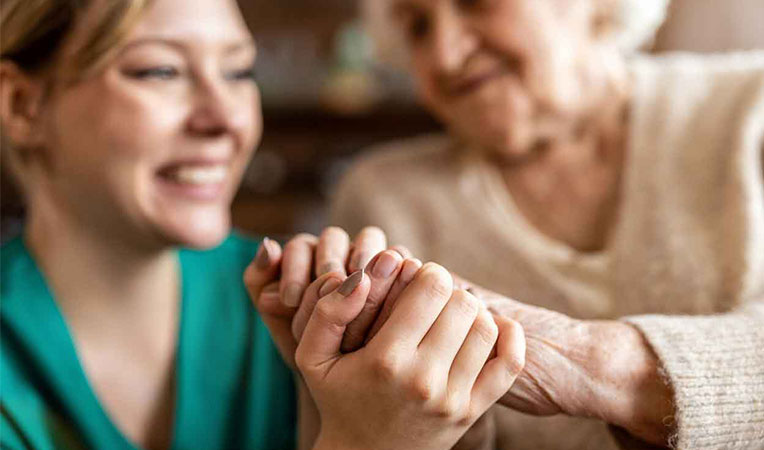 Two women holding hands, symbolizing SLB Eldercares support and compassion